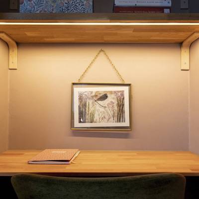 Un escritorio con una iluminación LED ambiental debajo del estante, así como un aplique de pared que resalta la obra de arte de un pájaro mediante una iluminación de acento.