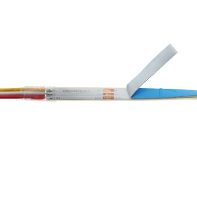 Detalle de tira de luz LED mostrando diodos, cables y adhesivo parcialmente retirado para instalación de iluminación.