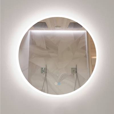 Un espejo de baño circular con retroiluminación LED resalta la moderna ducha, los azulejos geométricos y los apliques de luz dobles.