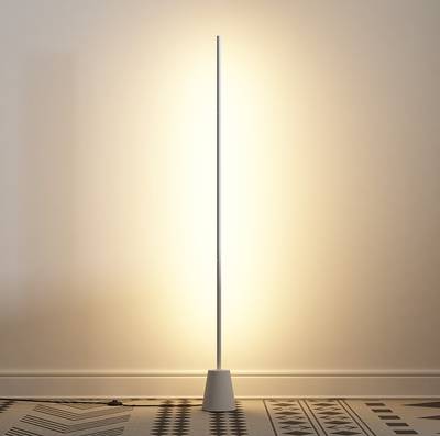 Lámpara de pie LED minimalista, diseño de poste delgado, luz ambiental cálida que ilumina el suelo y la pared con textura.