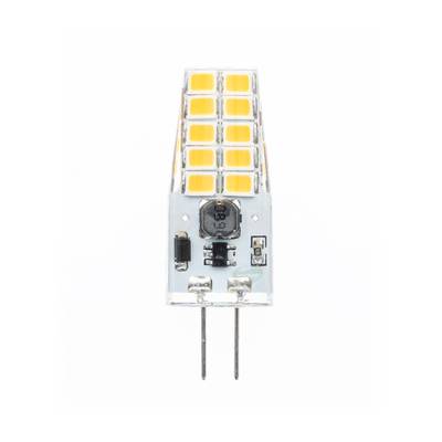 Primer plano de una pequeña lámpara LED con carcasa de plástico transparente, chips amarillos y dos clavijas inferiores para conexión eléctrica sobre fondo neutro.