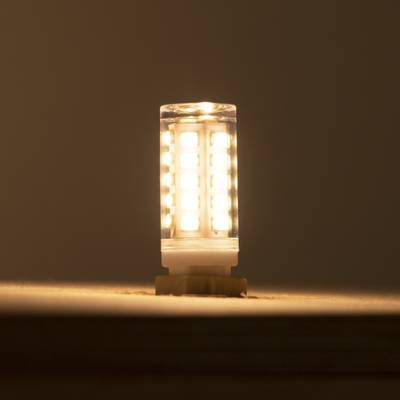Una cálida lámpara LED, que brilla sobre un fondo oscuro, colocada verticalmente para una óptima difusión de la luz y eficiencia energética. Perfecta para hogares ecológicos.