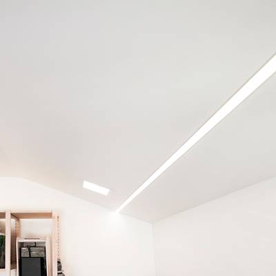 Techo de habitación minimalista con tiras de LED empotradas y luz LED cuadrada; estante de madera parcialmente visible en la esquina inferior izquierda.