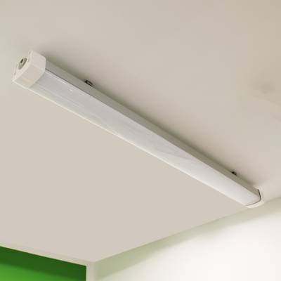Luminaria fluorescente blanca montada en el techo que ilumina una pared verde, ideal para ambientar tiendas con LED y ahorrar energía.