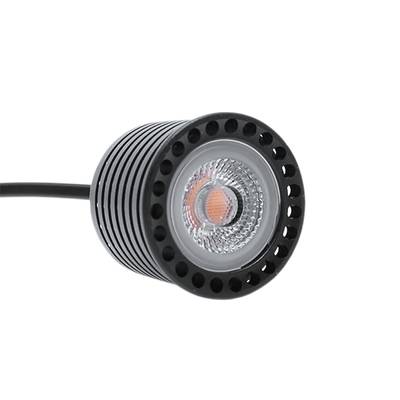 Primer plano de un foco LED circular con carcasa negra estriada, lente transparente y cable negro conectado. Una solución de iluminación energéticamente eficiente.