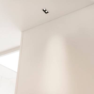 Una habitación minimalista con techo y paredes blancas y una elegante luminaria LED rectangular empotrada para una iluminación moderna.