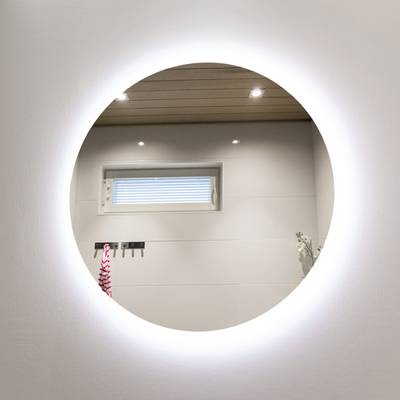 Texto alternativo:Espejo redondo con borde iluminado con LED que refleja la ventana y la ducha con una toalla de rayas rosas, realzando el ambiente moderno del cuarto de baño.
