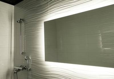 Este moderno cuarto de baño cuenta con azulejos blancos texturizados, un gran espejo retroiluminado y una elegante ducha y grifo plateados con iluminación LED.