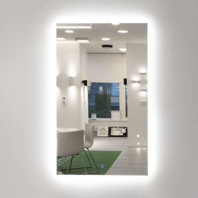 Un espejo iluminado que refleja un interior moderno con luces colgantes, sillas elegantes y luz natural.