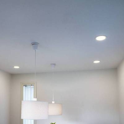 Techo con dos lámparas colgantes y tres empotradas iluminan una pared blanca en una tienda de iluminación LED.