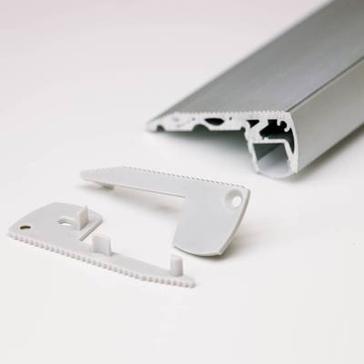 Primer plano de componentes de iluminación LED desmontados: riel de metal gris y piezas de plástico blanco con borde dentado. Luces LED de alta calidad en venta.
