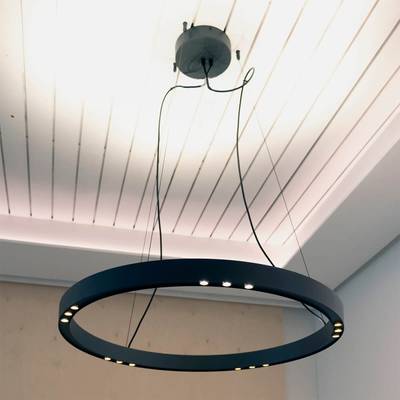 Elegante lámpara LED redonda con múltiples luces que cuelgan de un techo blanco. El cableado visible contribuye al ambiente industrial. Perfecta para interiores modernos.