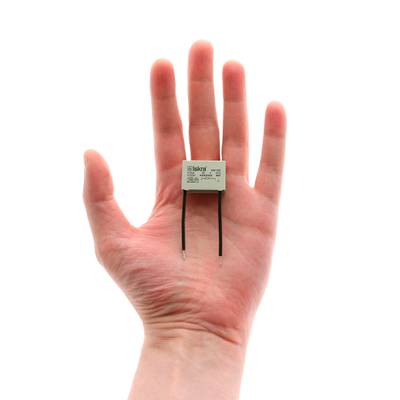 Primer plano de una mano con un componente de diodo LED de dos patillas, ideal para soluciones de iluminación energéticamente eficientes, sobre fondo blanco.