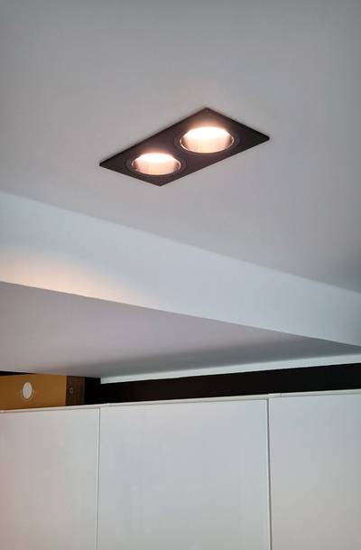 Techo con dos luces LED empotradas rectangulares que emiten luz cálida, vista parcial de los armarios y haz de luz desde abajo. Ideal para la iluminación del hogar moderno.