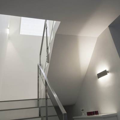 Escalera moderna con barandilla metálica, paredes grises e iluminación LED de pared que conduce a una pequeña ventana en la parte superior: iluminación de bajo consumo.