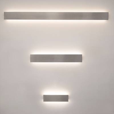 Tres luminarias LED rectangulares y verticales que irradian una luz cálida sobre una pared pálida; ideales para soluciones de iluminación domésticas modernas.