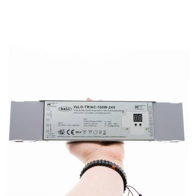 Primer plano de una mano sosteniendo el regulador LED VaLO TRIAC-100W-24V con pantalla digital, que mejora la eficiencia energética de la iluminación LED.