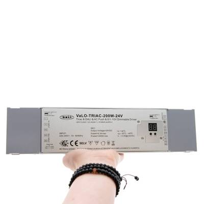 Controlador LED regulable VaLO TRIAC 200W-24V gris de mano con información del modelo y especificaciones en la superficie.
