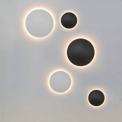 Cinco modernos apliques redondos, tres negros y dos blancos, irradian una luz cálida sobre un fondo claro. Elegante iluminación LED para interiores contemporáneos.