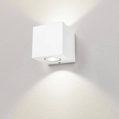 Un minimalista aplique cubo blanco ilumina una pared blanca de suave textura con luz ascendente y descendente. Perfecto para iluminación LED moderna.