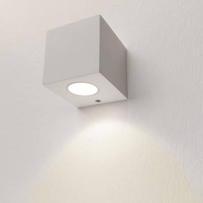 Texto alternativo: Aplique LED en forma de cubo ilumina una suave luz blanca sobre una pared con textura, un diseño de iluminación moderno para su hogar u oficina.