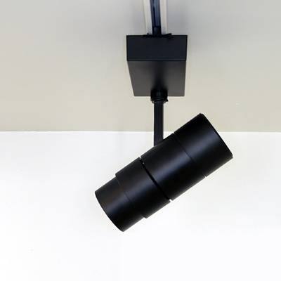 Foco cilíndrico negro en un sistema de raíles montado en el techo para soluciones de iluminación LED modernas.