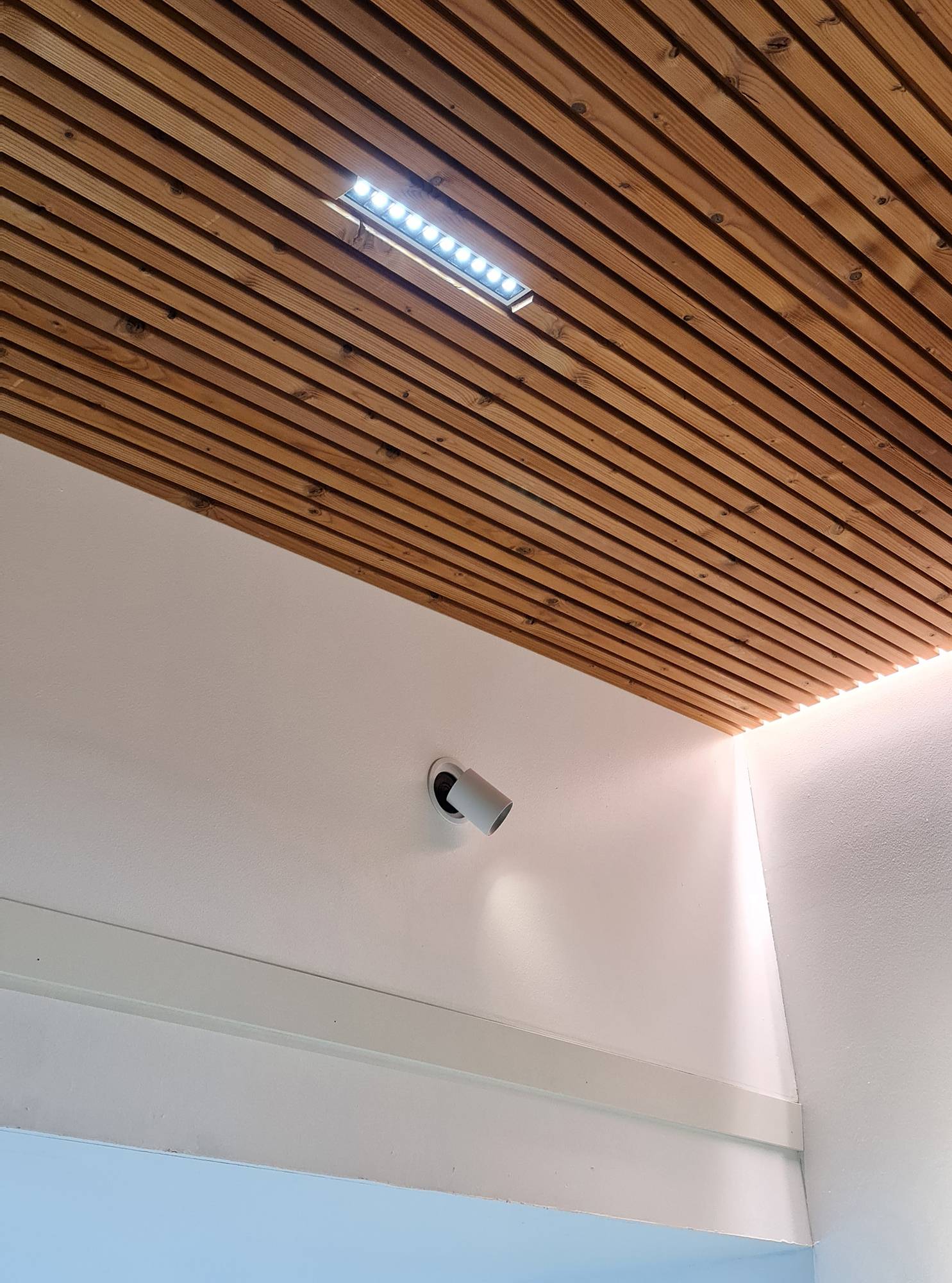 Luz indirecta en los bordes de la cornisa y proyector LINJA 10 que crea una iluminación general. Las luminarias LINJA 10 tienen un ángulo de luz muy estrecho, por lo que son ideales para techos altos. Foco direccional KOLO empotrado en la pared para la iluminación de acento de un cuadro. Ledstore.fi
