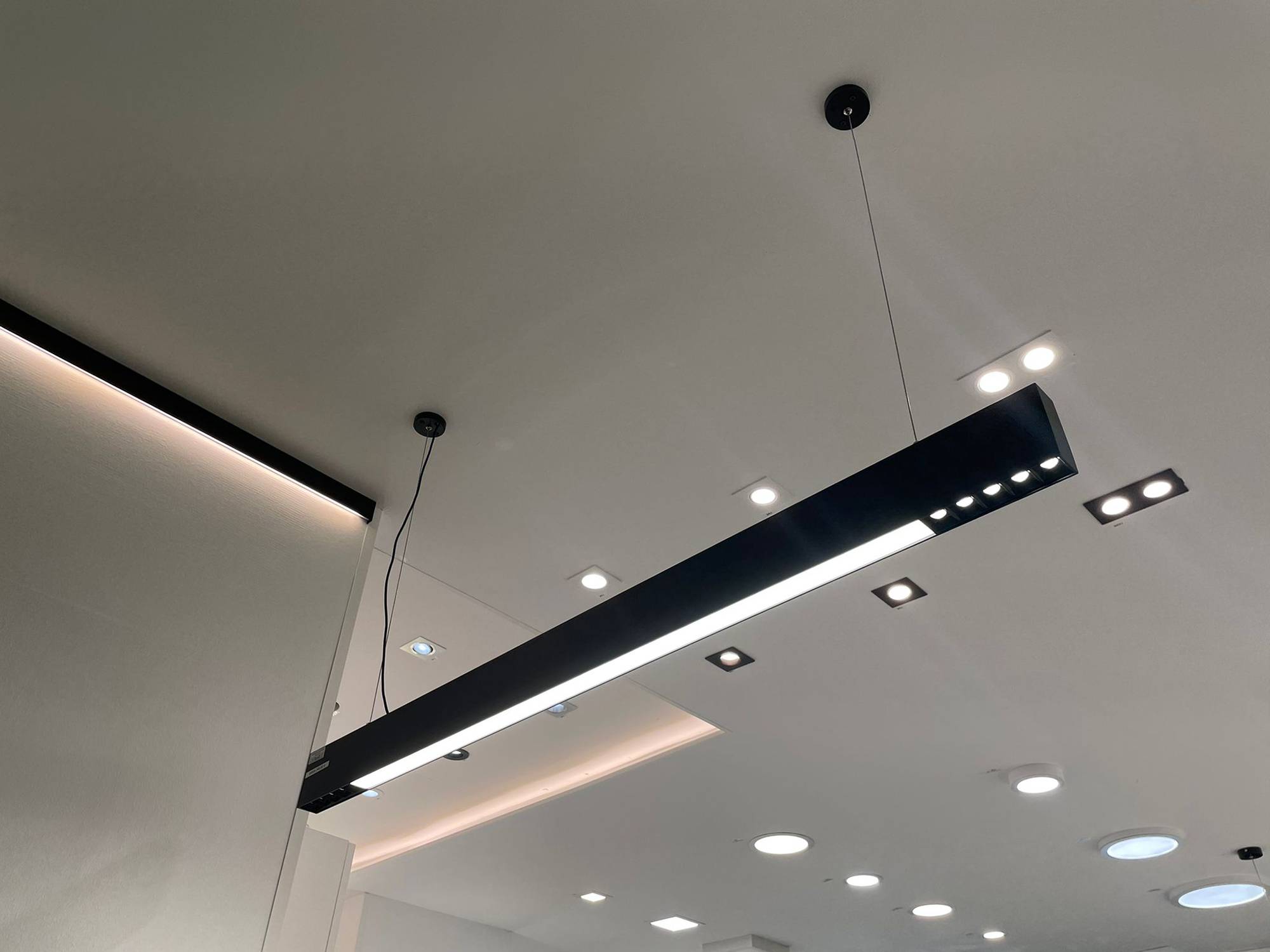 Luminaria Ledstorella Line sobre el mostrador de ventas. Tira de leds sobre perfil de aluminio de recambio en el techo para proporcionar luz indirecta y focos y paneles luminosos en el techo. Ledstore.fi
