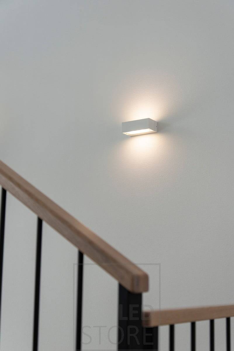 Aplique de pared bidireccional ANGULAR en una escalera. Brilla a través del cristal grabado con una luz suave y atmosférica. Ledstore.fi