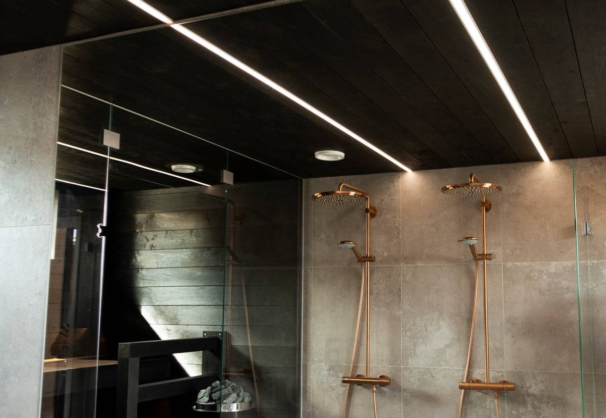 Feria de la Vivienda 2020: tiras de leds iluminando el baño en estrechos perfiles empotrados en el techo negro del lavabo. Las líneas de luz iluminan el espacio con una luz agradable y de alta calidad. Ledstore.fi