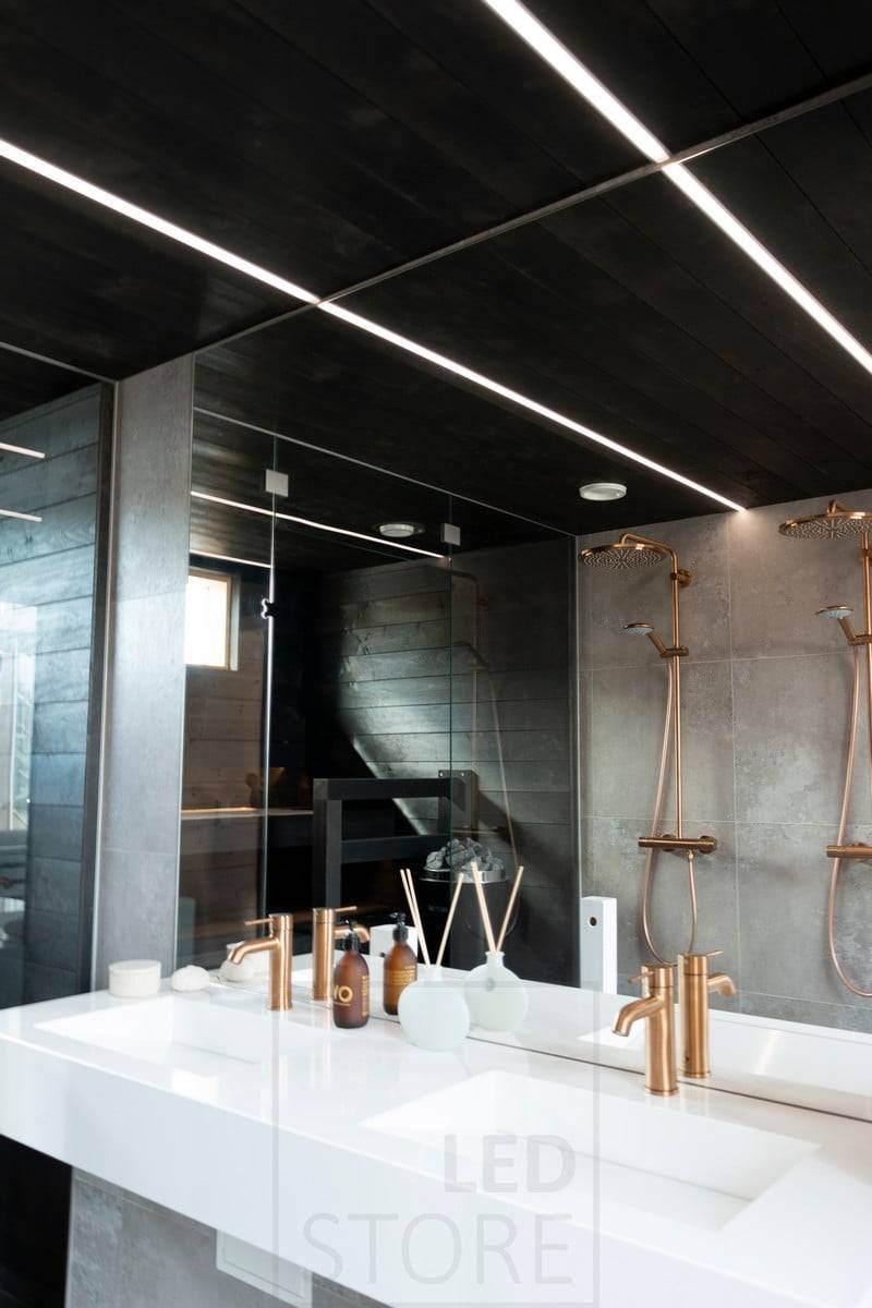 Feria de la Vivienda 2020: tiras de leds iluminando el baño en estrechos perfiles empotrados en el techo negro del lavabo. La iluminación crea bellas líneas de luz en el techo. Ledstore.fi