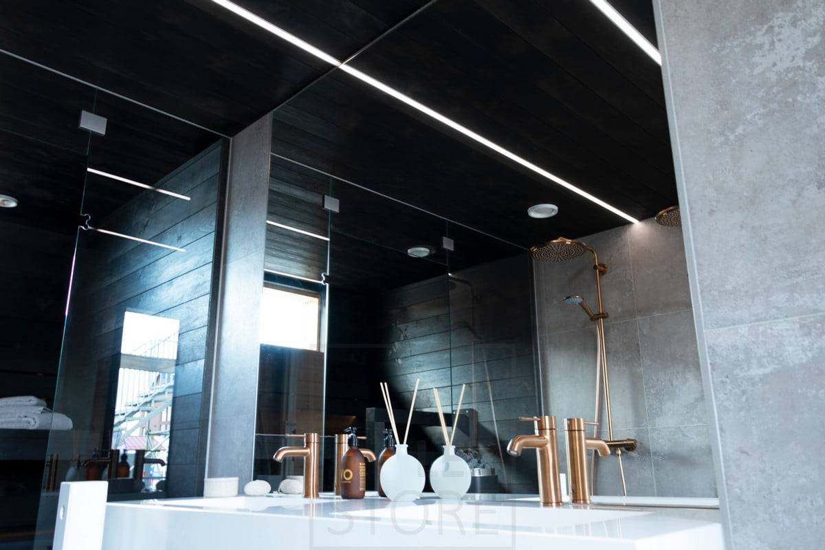 Feria de la Vivienda 2020: tiras de led iluminando el baño en estrechos perfiles empotrados en el techo negro del lavabo. Ledstore.fi