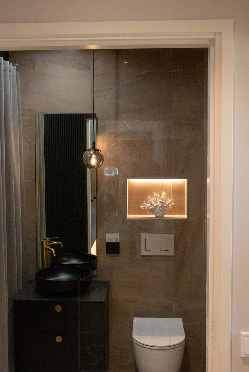 Feria de la Vivienda 2022: Una estantería en el cuarto de aseo, empotrada en la pared, lleva una tira de LED para resaltar el detalle. Una lámpara colgante como elemento decorativo atmosférico. Ledstore.fi
