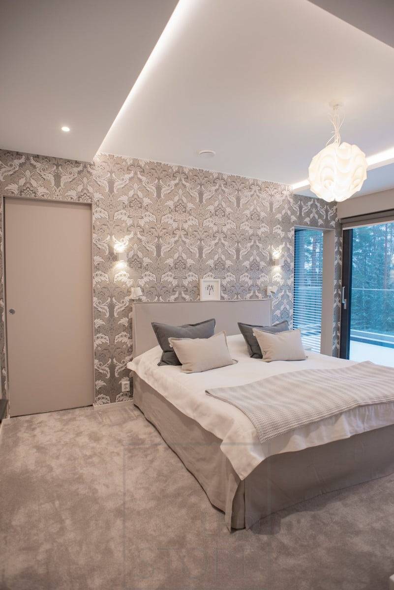 En el dormitorio, los apliques led CUBIC a ambos lados de la cama proporcionan luz ambiental y de lectura en dos direcciones. Esta luminaria minimalista combina a la perfección con el papel pintado estampado. Ledstore.fi