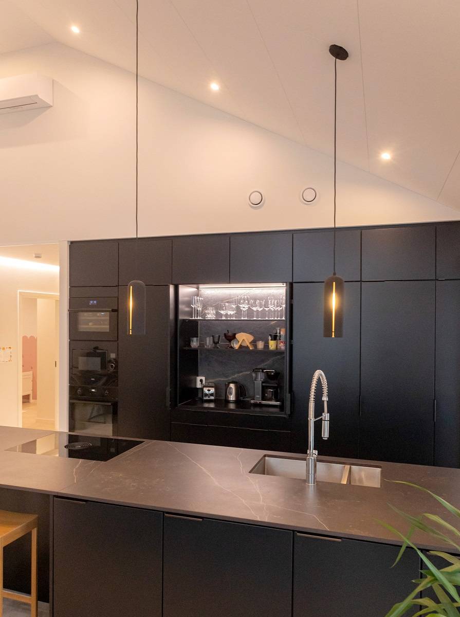 Mueble de desayuno con tiras de LED y focos en el techo inclinado de la cocina.