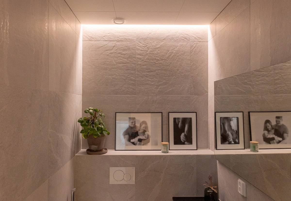Tira de LED empotrada entre la pared y el techo en un aseo.