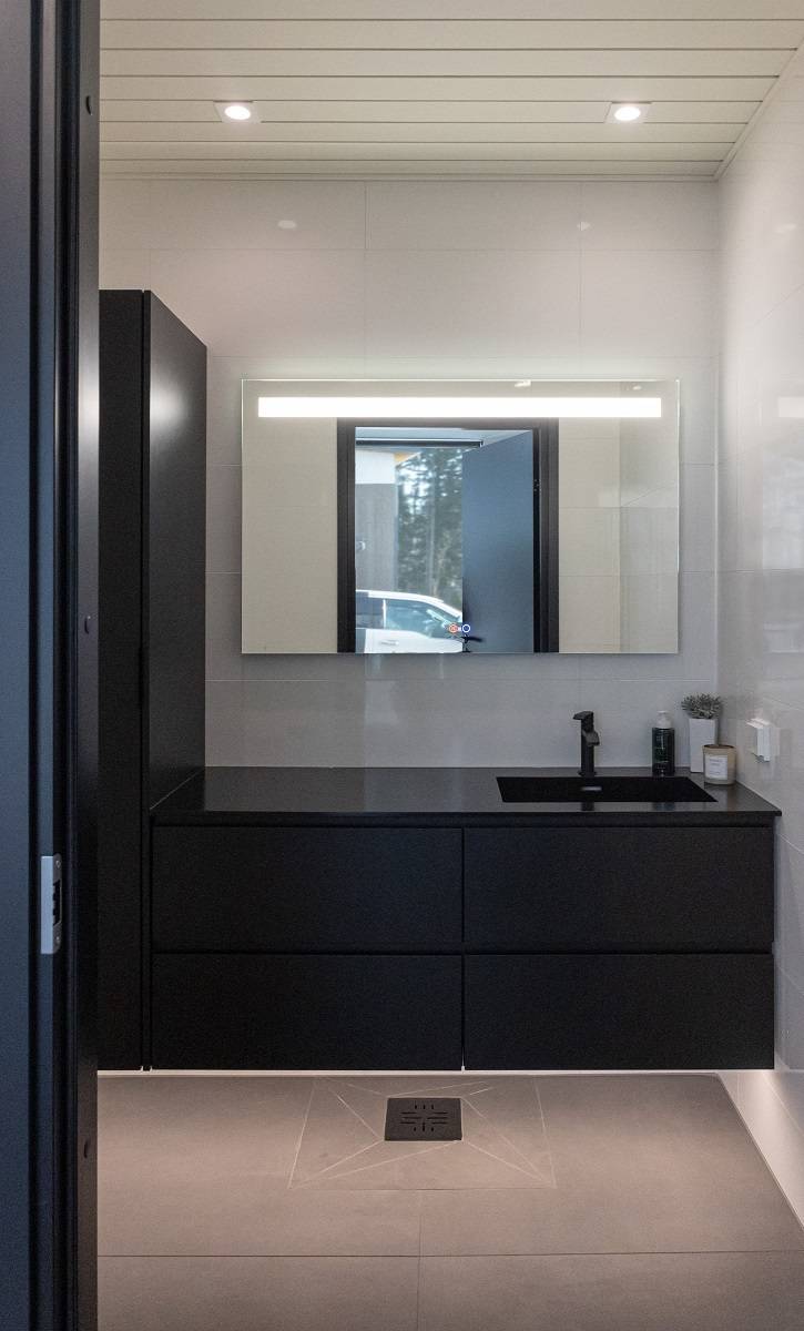 Cuarto de baño con tira de LED bajo los armarios para luz indirecta, lámpara de espejo SEELIA y dos downlights LED SQ023 en el techo.