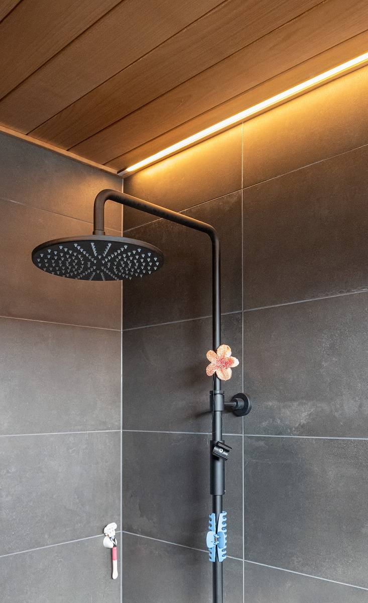 Cuarto de baño con tira de LED empotrada en el techo junto a la pared.