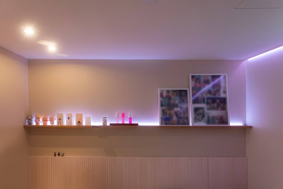 Una tira de LED que emite luz lila rodea la habitación; además, en el techo hay dos focos.