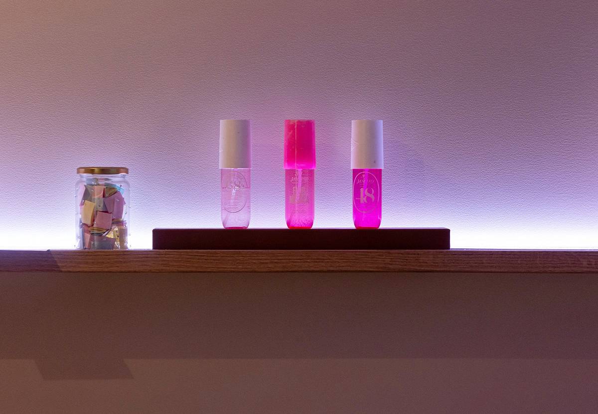 La tira de LED con colores regulables instalada detrás de la estantería proyecta un resplandor violeta en la pared.