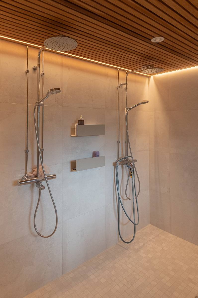En el cuarto de baño, una tira de LED iluminada en el borde del techo. Además, hay un foco empotrado en el techo que no está encendido.