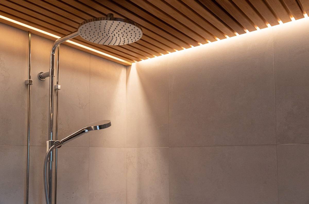 En el techo de listones de la ducha hay una tira de LED empotrada.