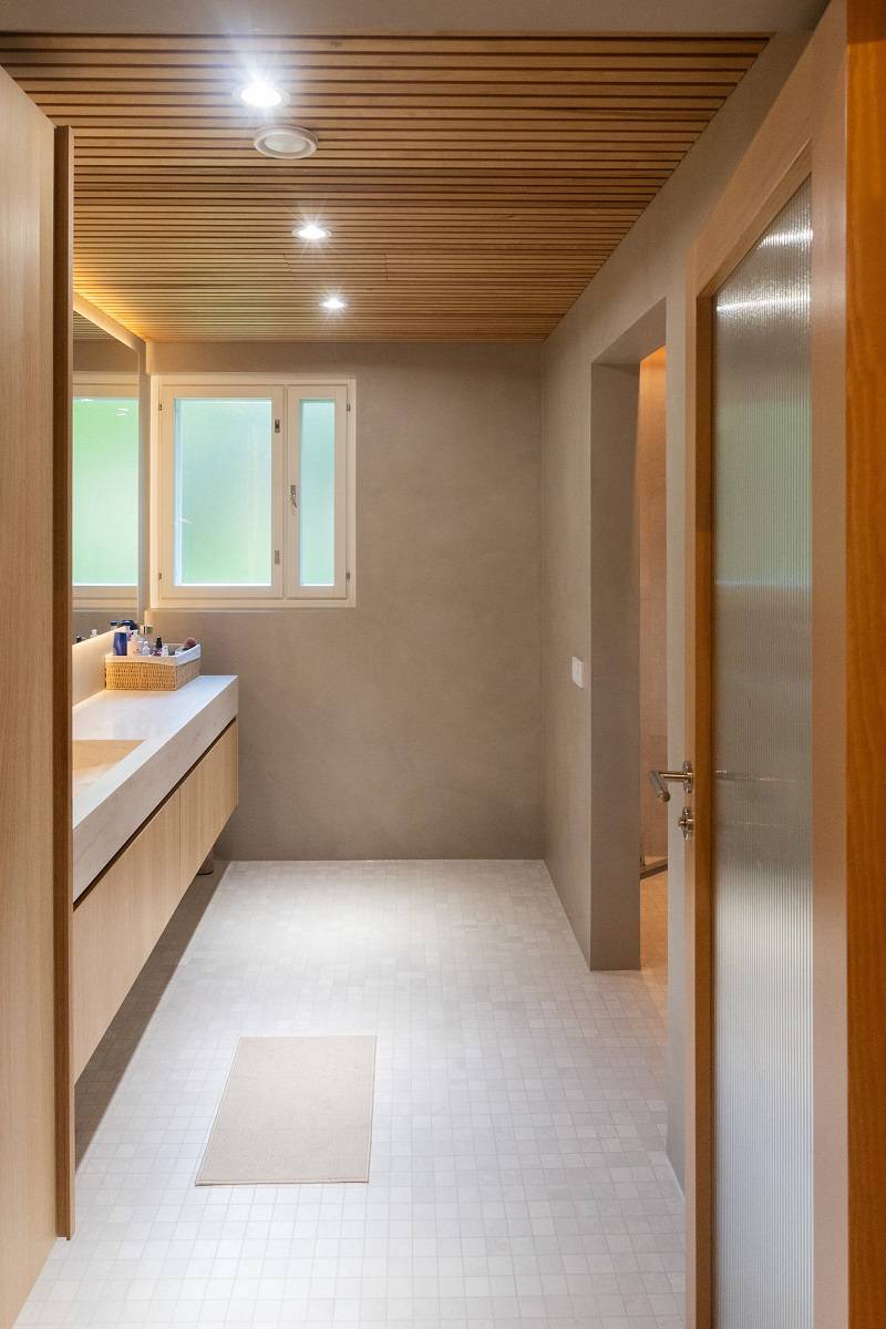 Los focos y la tira de LED situados detrás del espejo iluminan la zona del lavabo del baño.