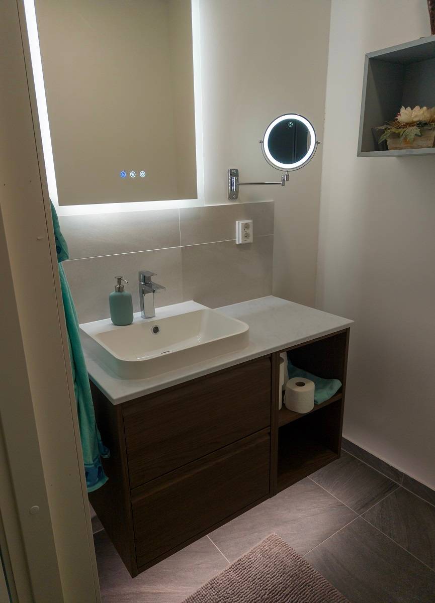 Además de la tira de leds en el baño, un espejo de luz y una pequeña lámpara de panel redondo