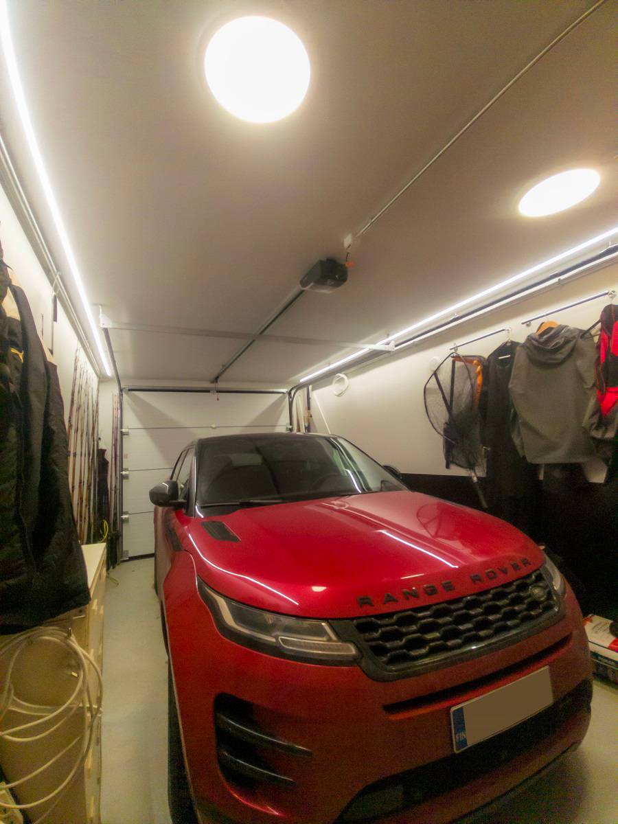 En el techo de un garaje, a ambos lados hay tiras de led. También hay dos plafones de leds en el techo.