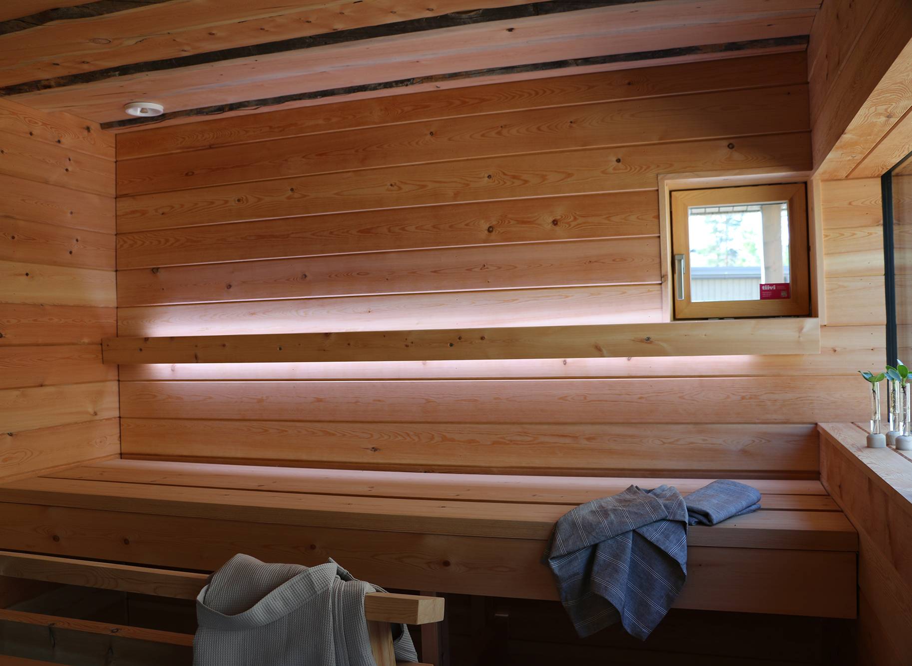 Iluminación de sauna con tiras de leds en el respaldo. Las tiras de leds iluminan hacia arriba y hacia abajo. Ledstore.fi