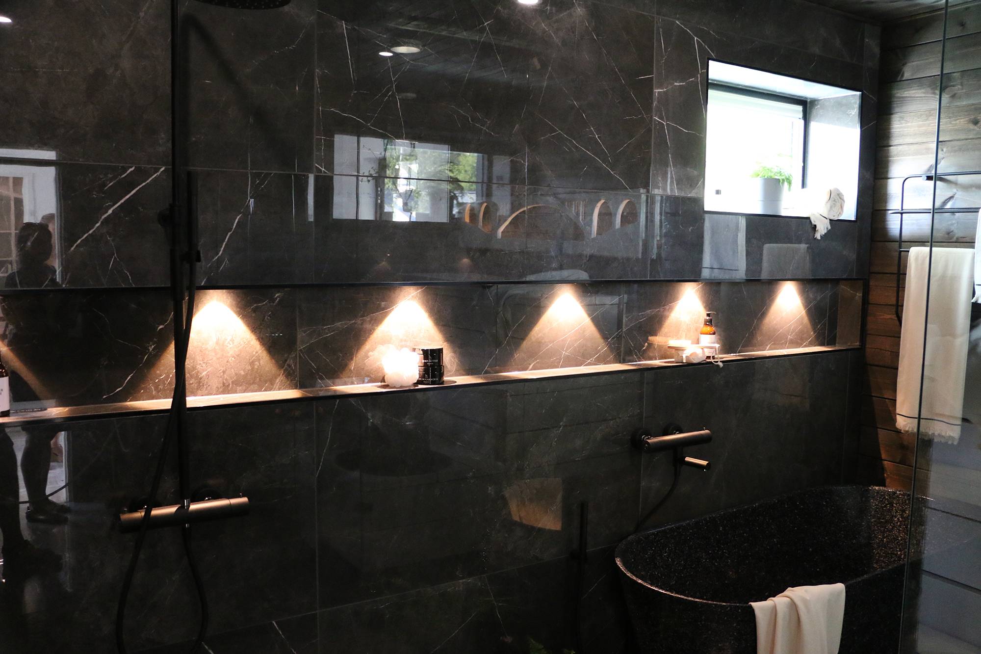 En el cuarto de baño, los focos resaltan el estante del champú. Ledstore.fi