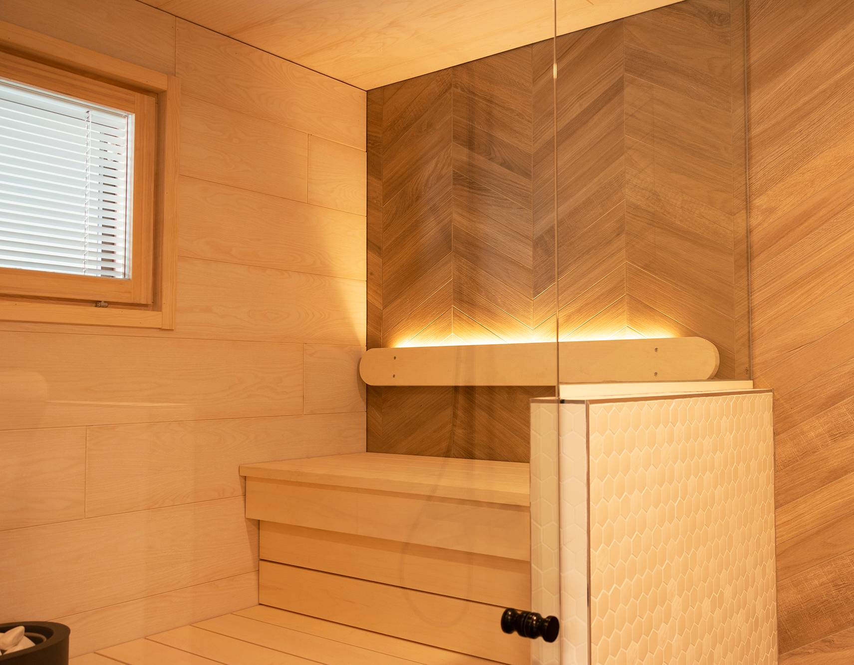 Iluminación de la sauna implementada con una tira de leds en el respaldo orientada hacia arriba. La iluminación del lavabo también ilumina la sauna gracias a las paredes de cristal. Ledstore.fi
