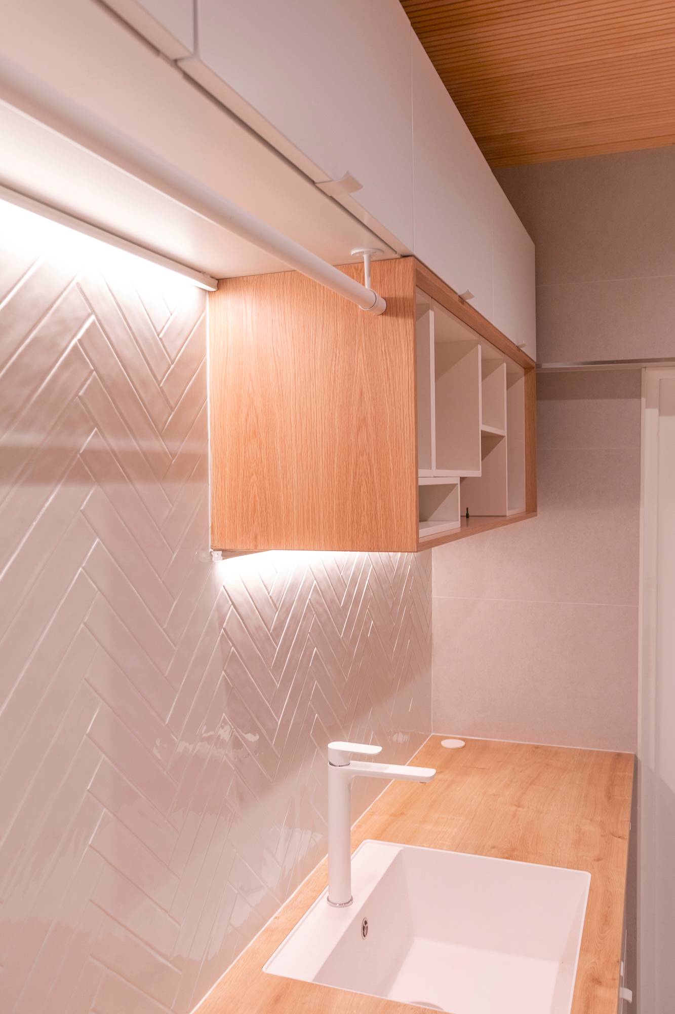 Dos niveles de tiras de LED montadas bajo los armarios iluminan la encimera y resaltan los azulejos texturizados.