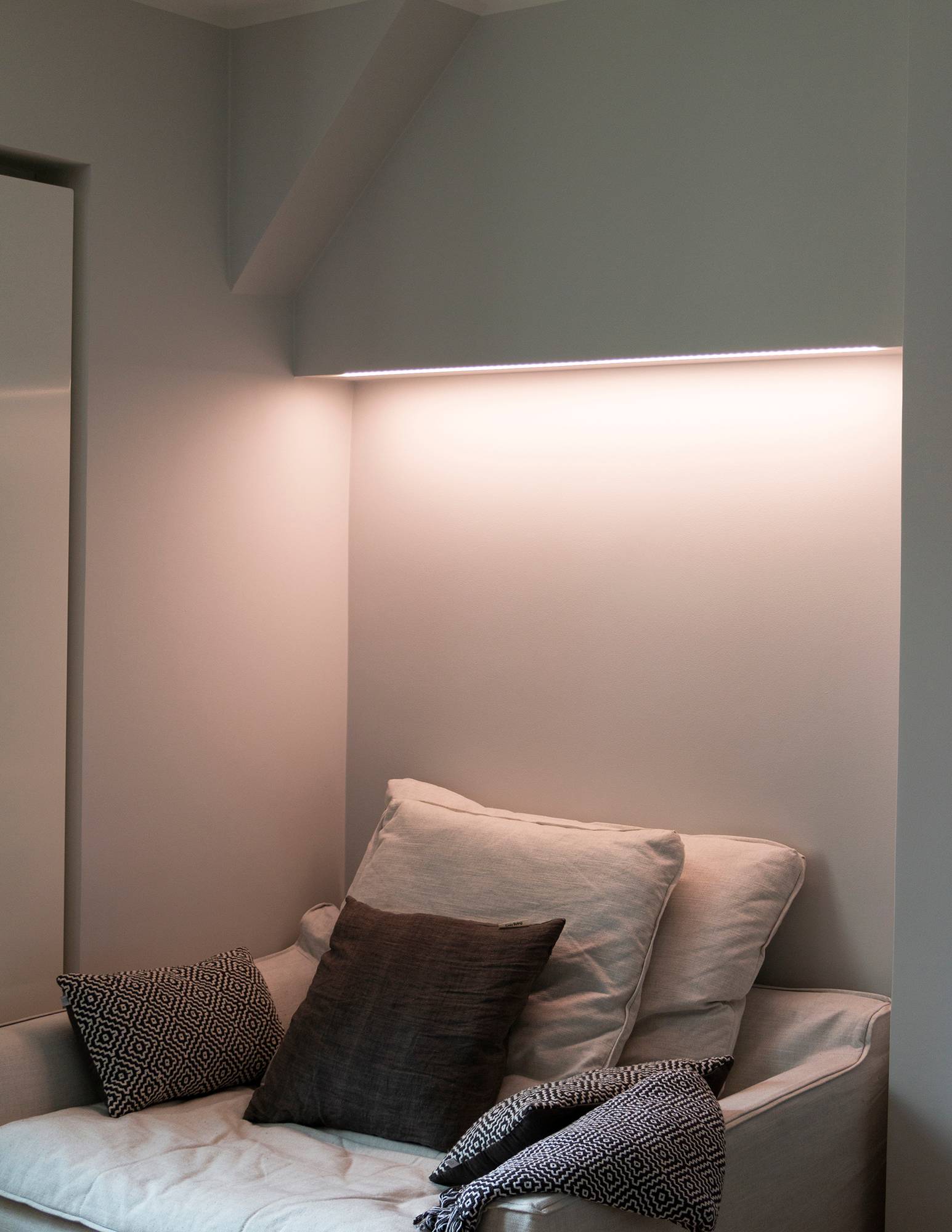Dormitorio con iluminación ambiental controlada por temperatura de color detrás de la cama, tira de leds fijada a la parte inferior del mueble en una superficie de perfil bajo. Ledstore.fi